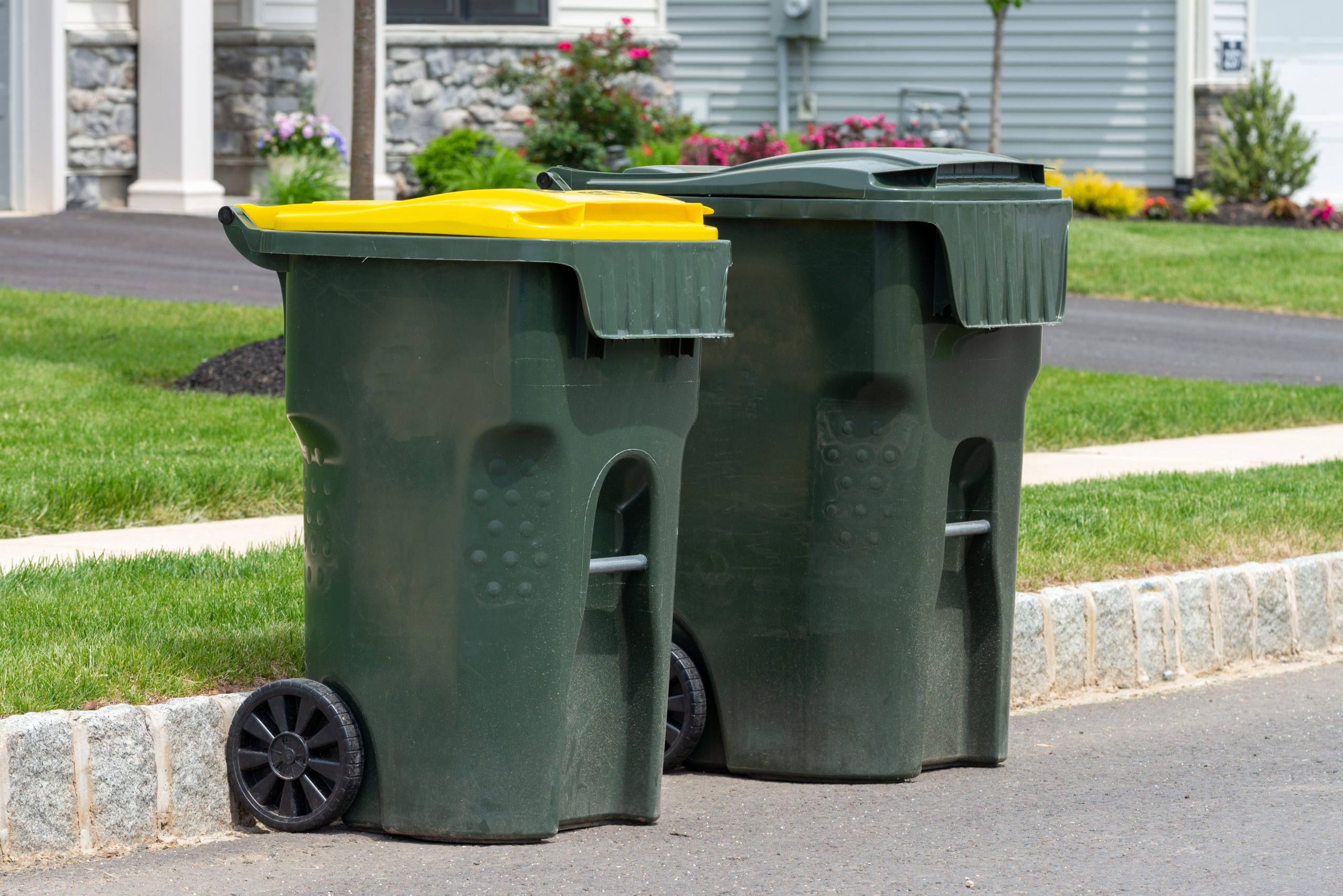 big empty green plastic trash garbage bin in front of the modern house junk road public